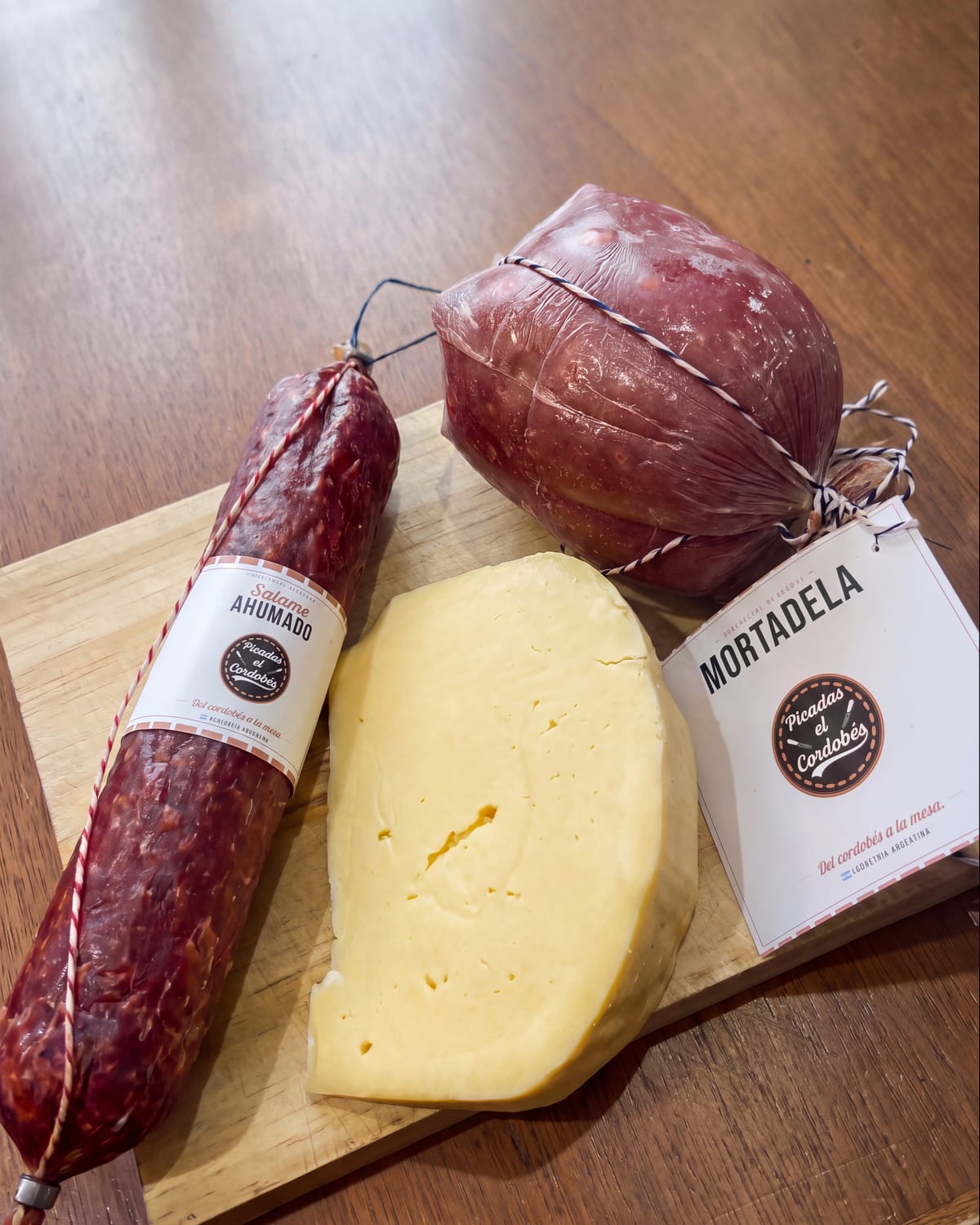 Salame ahumado, mortadela y queso de Picadas El Cordobés sobre una tabla de madera